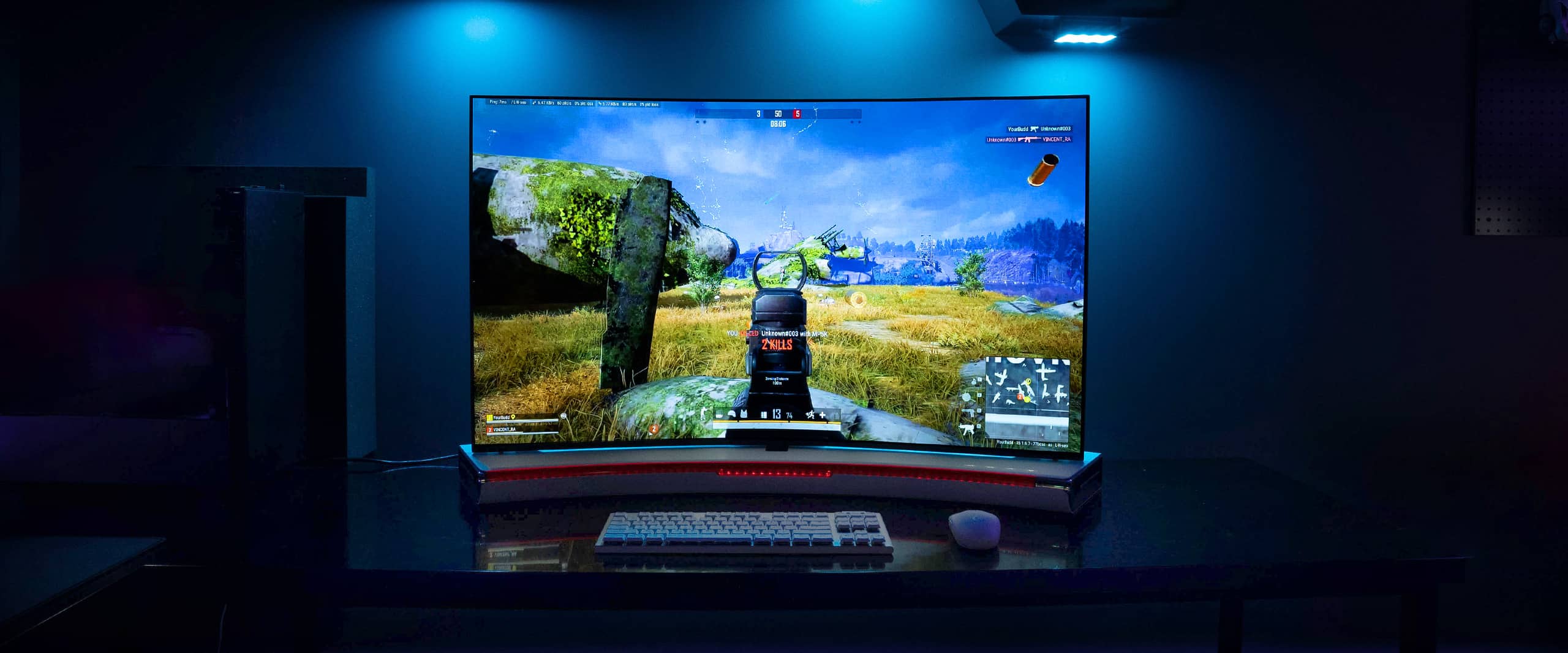 The game is being played on the Bendable Gaming OLED display, and keyboards and monitors are visible below.