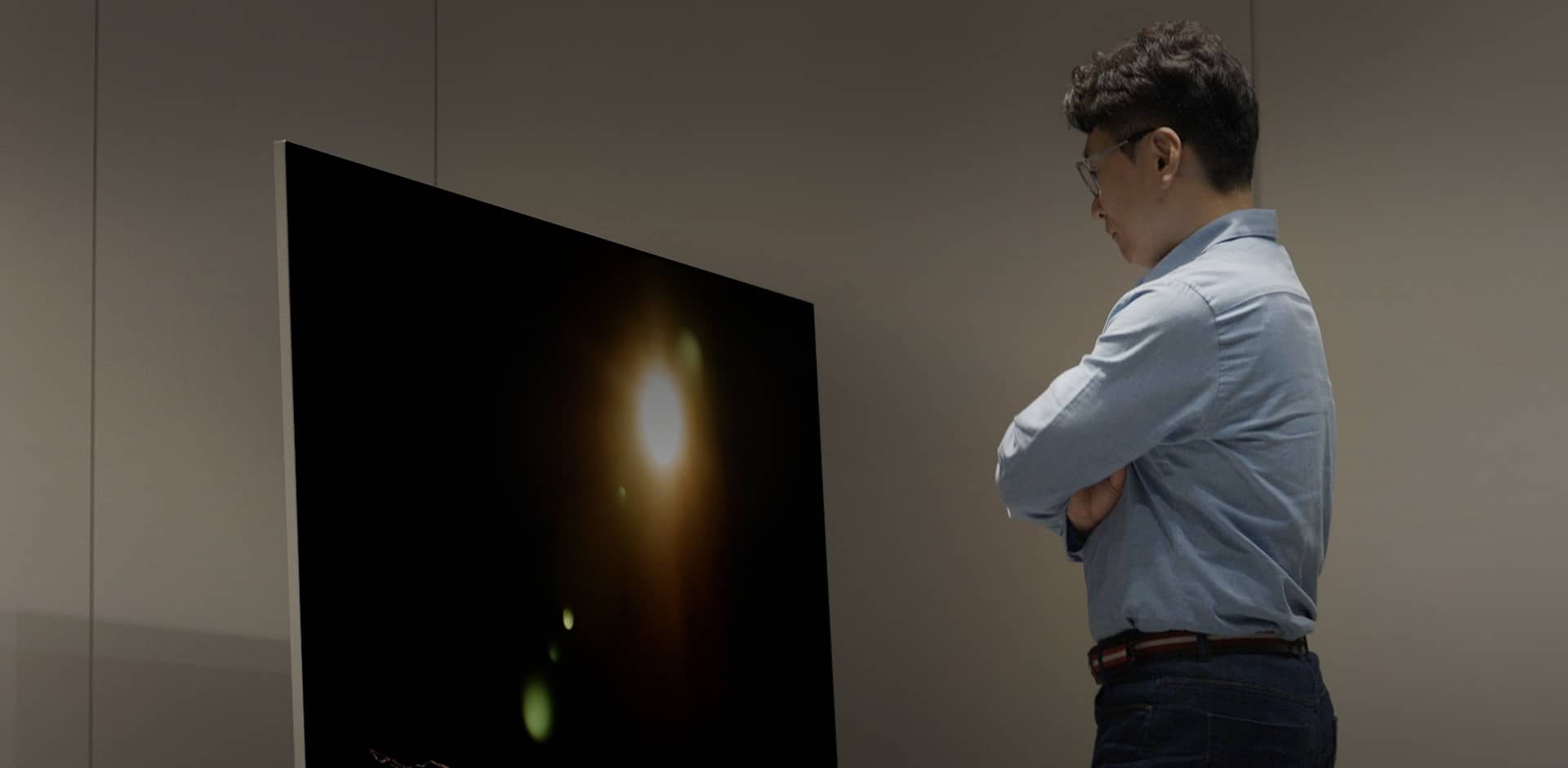  Dr. Yang is looking at the 3rd Genenration OLED META Technology display with his arms crossed. 