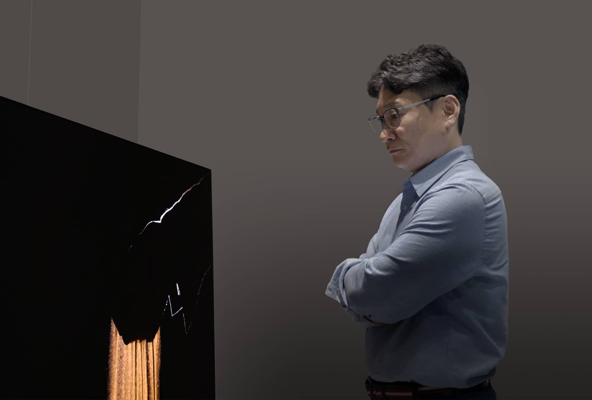  Dr. Yang is looking at the 3rd Generation OLED META Technology display with his arms crossed. 