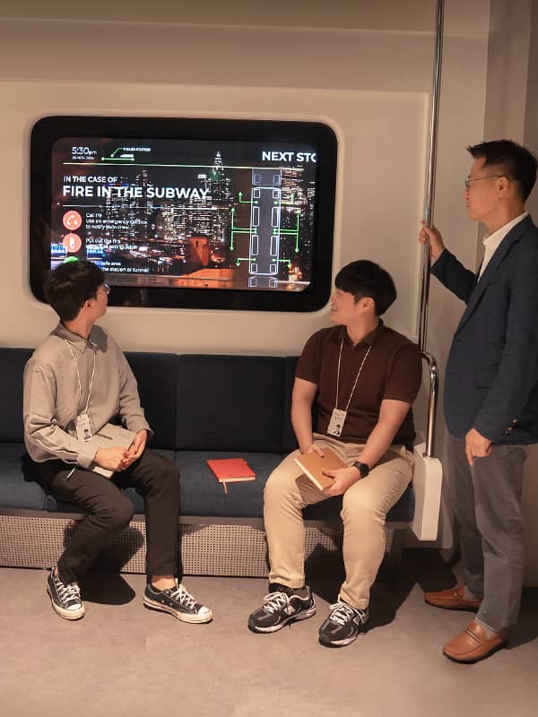 김빈 책임이 지하철 창문에 설치된 투명 OLED 화면을 바라보며 팀원들과 논의를 나누고 있다.